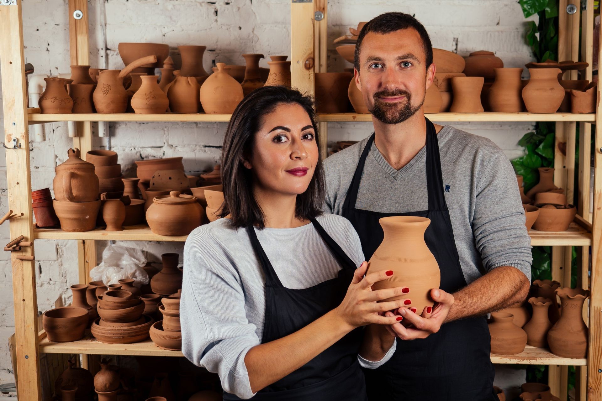 handsome man and happy woman couple in love working on potter wheel while at pottery workshop. husband and wife in the kraft creative studio,young family business shop sculpts pot from clay